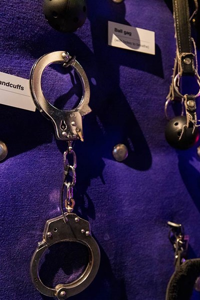 Handcuffs attached to a purple wall in the Red Light Secrets Museum.